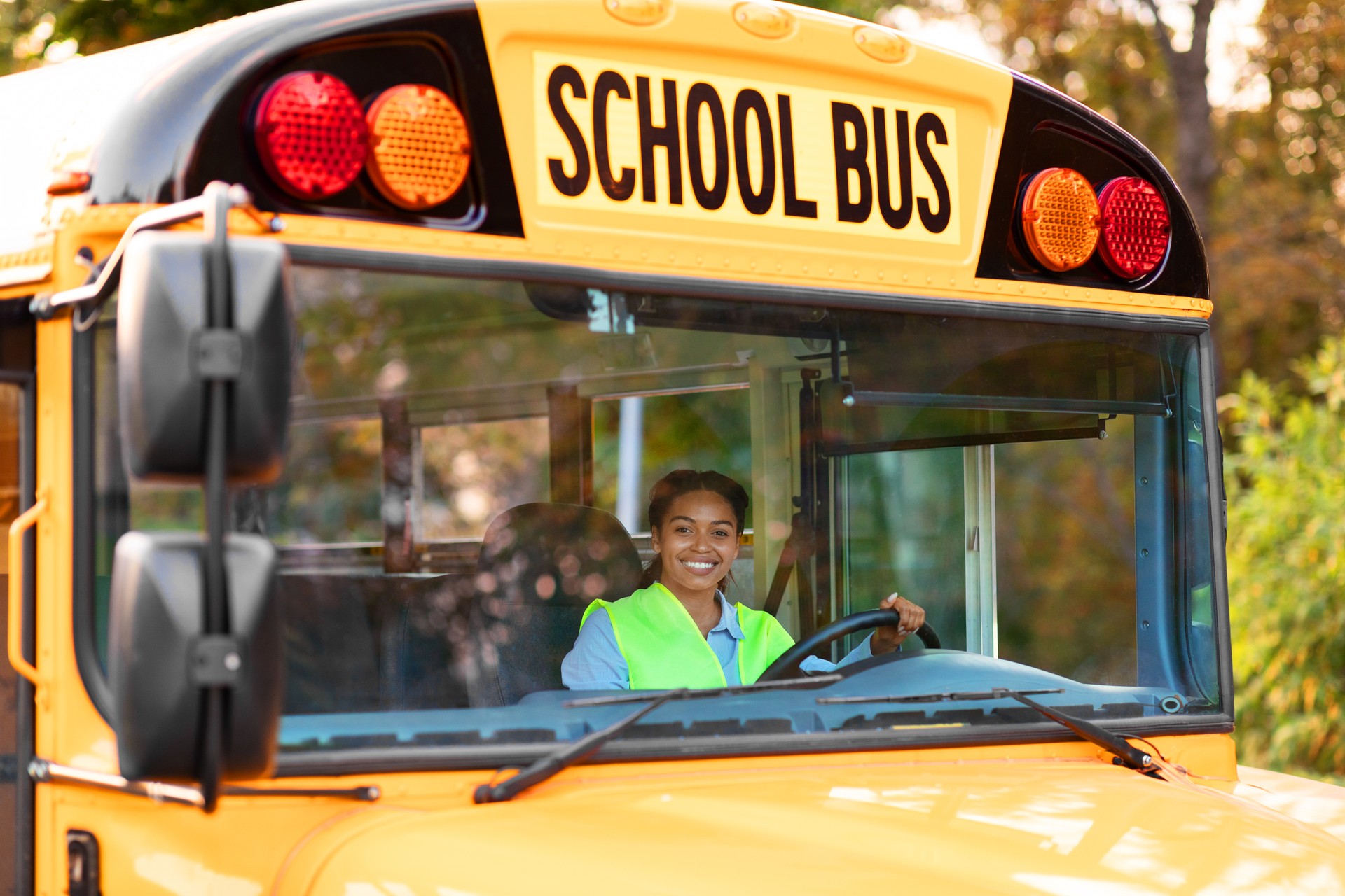 Portrait Of Happy Black Female Driver Driving Yellow School Bus